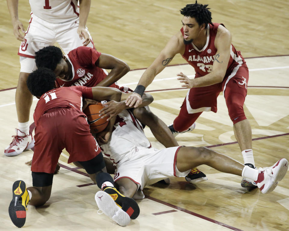 Alabama's Joshua Primo (11), Herbert Jones (1), and James Rojas (33) fight for the ball with Oklahoma's Elijah Harkless (24) during the second half of an NCAA college basketball game in Norman, Okla., Saturday, Jan. 30, 2021. (AP Photo/Garett Fisbeck)