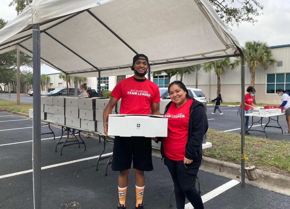Achievers alums Jelani Mays, left, and Regina Mantero volunteer during the November 2021 distribution of nearly 800 Thanksgiving meals to families in need.