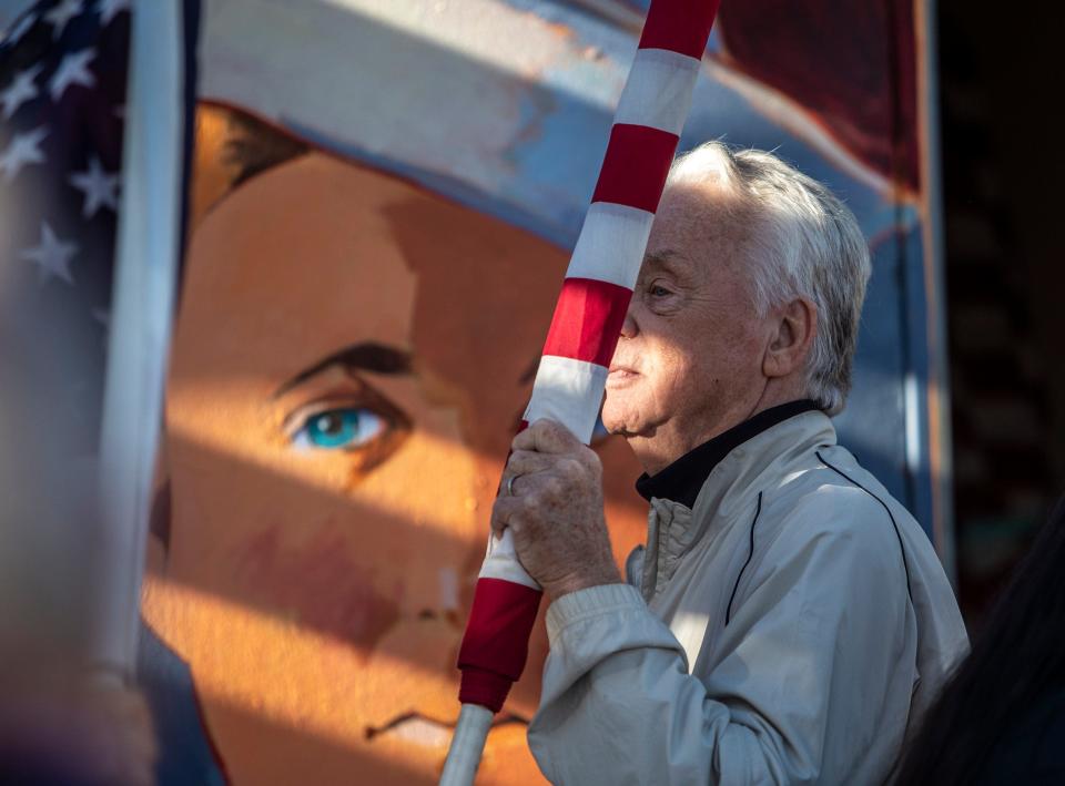 Volunteer John Purdy carries out an American flag to be looked over and reconditioned before being placed during a Fields of Valor event at Patriot Park in Cathedral City, Calif., Saturday, Nov. 5, 2022.