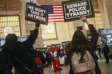 Activists hold placards as a woman leads a demonstration against police brutality in Grand Central Terminal in New York January 19, 2015. REUTERS/Adrees Latif