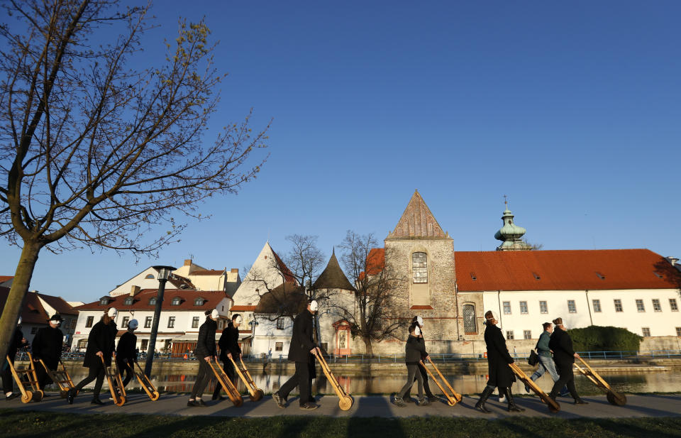 In this picture taken on Thursday, April 18, 2019, participants dressed in black, wearing masks, beating drums and pushing small carts that make a synchronized and loud sound take part in an Easter procession through the streets of Ceske Budejovice, Czech Republic. (AP Photo/Petr David Josek)