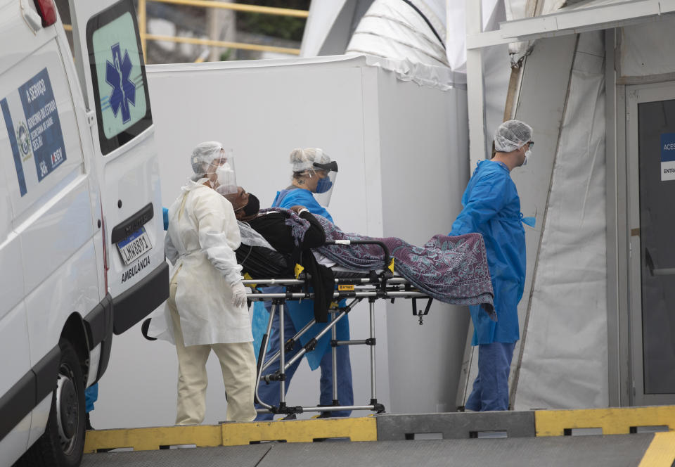 A patient with symptoms related to COVID-19 is brought to a field hospital by workers in full protective gear in Leblon, Rio de Janeiro, Brazil, Thursday, June 4, 2020. (AP Photo/Silvia Izquierdo)