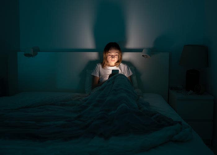 mujer con el móvil en la cama