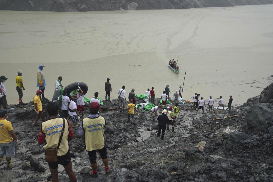 A small boat with people onboard approaches an area where bodies are recovered Friday, July 3, 2020, in Hpakant, Kachin State, Myanmar. More than 100 people were killed Thursday in a landslide at a jade mine in northern Myanmar, the worst in a series of deadly accidents at such sites in recent years.(AP Photo/Zaw Moe Htet)