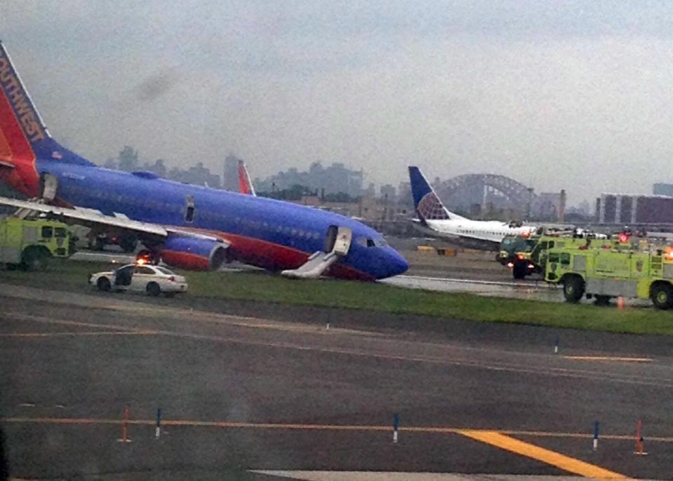 In this photo provided by Jared Rosenstein, a Southwest Airlines plane whose nose gear collapsed as it touched down on the runway is surrounded by emergency vehicles at LaGuardia Airport in New York on Monday, July 22, 2013. The plane was carrying 149 passengers and crew. (AP Photo/Jared Rosenstein) MANDATORY CREDIT