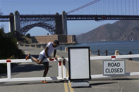 A runner climbs over a road gate leading to Fort Point National Historic Site, which has been closed due to the federal government shutdown, in San Francisco, California October 2, 2013. REUTERS/Stephen Lam