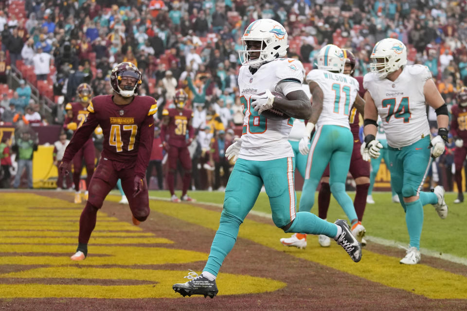 Miami Dolphins running back De'Von Achane, middle, scores on a touchdown run in front of Washington Commanders linebacker Khaleke Hudson (47) during the second half of an NFL football game Sunday, Dec. 3, 2023, in Landover, Md. (AP Photo/Alex Brandon)