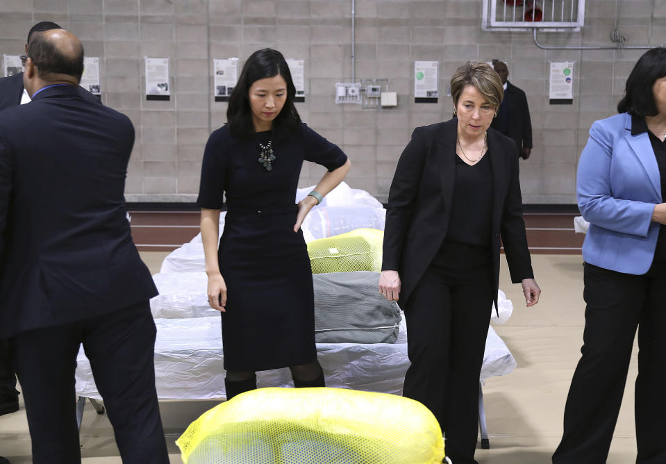 Boston Mayor Michelle Wu, left, and Massachusetts Governor Maura Healey pause to look at the Army cots set up on the gym floor as State and local officials toured the Melnea A. Cass Recreational Complex, Wednesday, Jan. 31, 2024, in the Roxbury neighborhood of Boston. The facility will house over 300 migrants. (John Tlumacki/The Boston Globe via AP, Pool)
