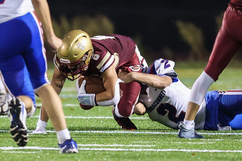 Portsmouth's Emmanuel Poe tries to pick up additional yards as Winnacunnet's DJ Sciacca makes the tackle in Friday's Division I football game.