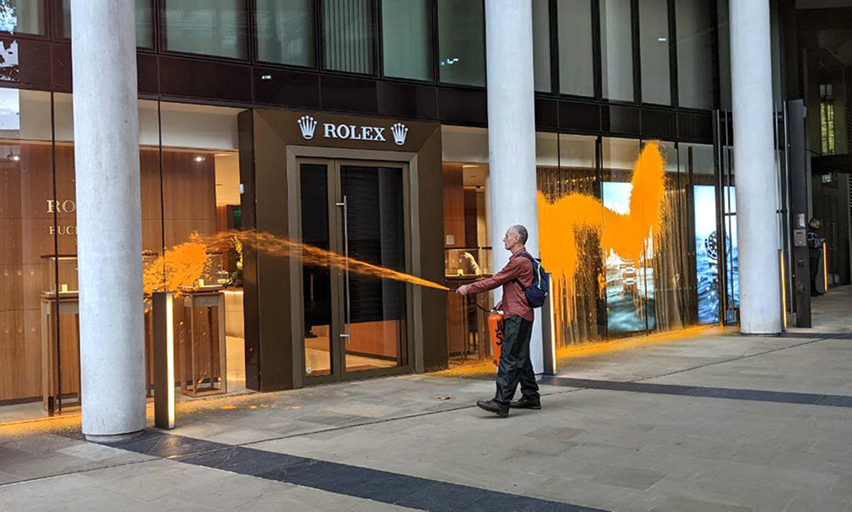 Handout photo issued by Just Stop Oil of one of their activists spraying orange paint over the windows of the Rolex showroom in Knigtsbridge, London. Issue date: Friday October 28, 2022.