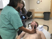 In this Aug. 2, 2019 photo, students practice with each other using a Butterfly iQ handheld ultrasound device attached to a tablet during a class at Indiana University medical school in Indianapolis. The device shows instant images of the heart and other organs, helping doctors diagnose a range of ailments. (AP Photo/Lindsey Tanner)