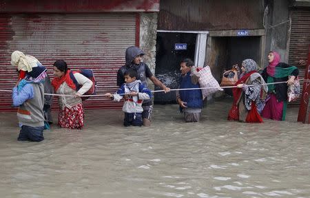 Kashmiri people walk with the help of a rope through a flooded street during rain in Srinagar September 6, 2014. REUTERS/Danish Ismail