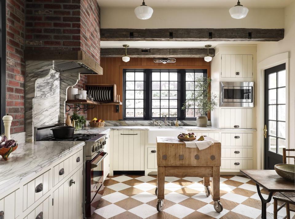 rustic kitchen with cream cabinetry and oak flooring painted in a cream and natural wood checkerboard pattern set on the diagonal