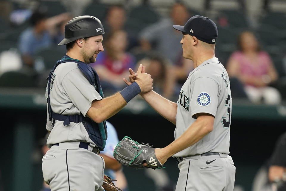 Seattle Mariners relief pitcher Paul Sewald (37) and catcher Cal Raleigh celebrate the final out of the10th inning of a baseball game against the Texas Rangers in Arlington, Texas, Sunday, June 5, 2022. (AP Photo/LM Otero)