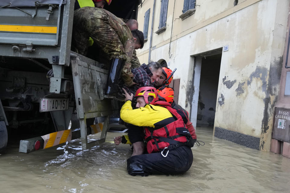 Firefighters rescue an elderly man in the flooded village of Castel Bolognese, Italy, Wednesday, May 17, 2023. Exceptional rains Wednesday in a drought-struck region of northern Italy swelled rivers over their banks, killing at least eight people, forcing the evacuation of thousands and prompting officials to warn that Italy needs a national plan to combat climate change-induced flooding. (AP Photo/Luca Bruno)