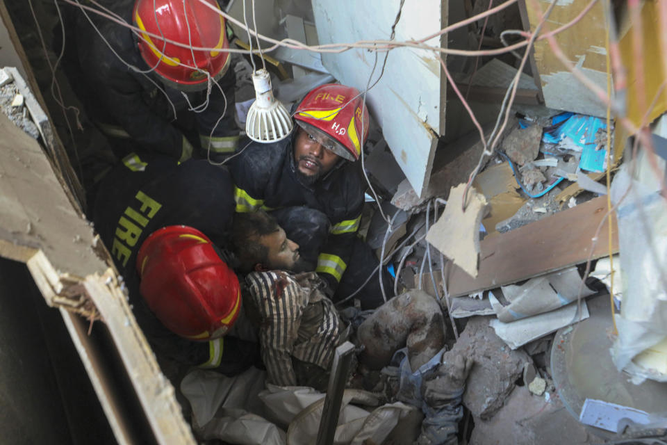 Fire officials rescue an injured person from the debris of a commercial building after an explosion, in Dhaka, Bangladesh, Tuesday, March 7, 2023. An explosion in a seven-story commercial building in Bangladesh's capital has killed at least 14 people and injured dozens. Officials say the explosion occurred in a busy commercial area of Dhaka. (AP Photo/Abdul Goni)