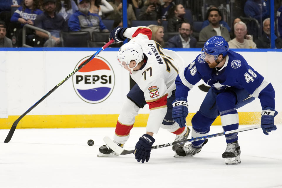 Florida Panthers defenseman Niko Mikkola (77) loses the puck after he gets hit by Tampa Bay Lightning defenseman Nick Perbix (48) during the first period of an NHL hockey game Wednesday, Dec. 27, 2023, in Tampa, Fla. (AP Photo/Chris O'Meara)