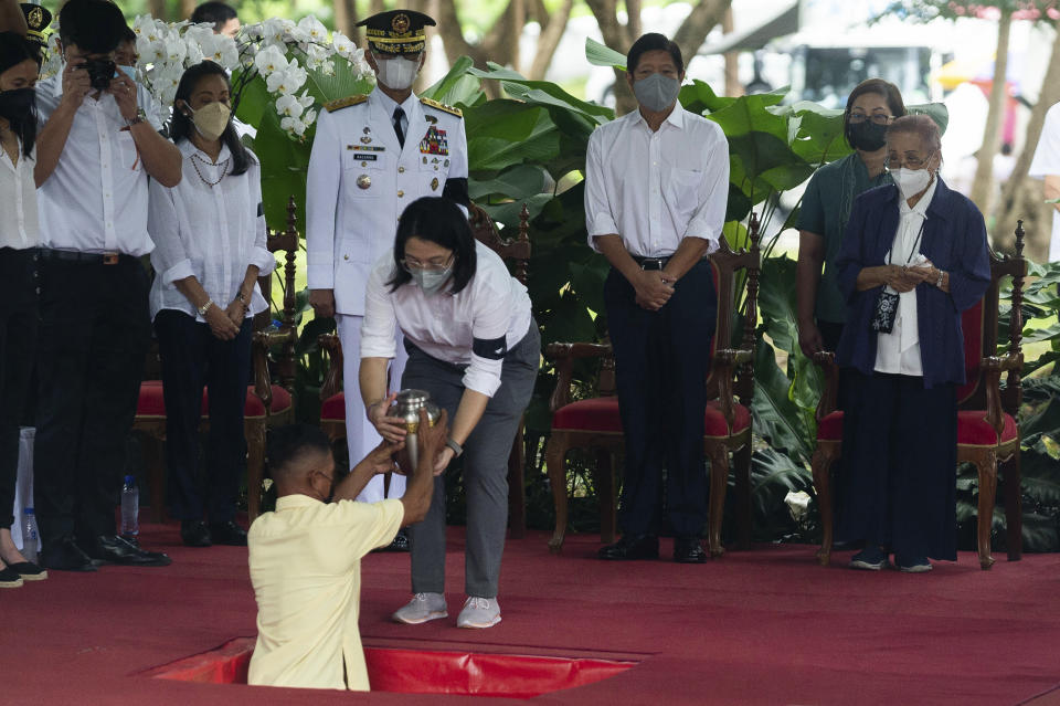 The grandchild of former Philippine President Fidel Ramos, center, hands over the urn in front of Philippine President Ferdinand Marcos Jr., third right, and Amelita Ramos, right, wife of the former president, during a state funeral at the Heroes' Cemetery in Taguig City, Philippines, Tuesday, Aug. 9, 2022. Ramos was laid to rest in a state funeral Tuesday, hailed as an ex-general, who backed then helped oust a dictatorship and became a defender of democracy and can-do reformist in his poverty-wracked Asian country. (Lisa Marie David/Pool Photo via AP)