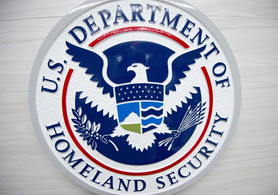 The Department of Homeland Security logo, with an escutcheon on top of an eagle with spread wings holding an olive branch and eight arrows. 