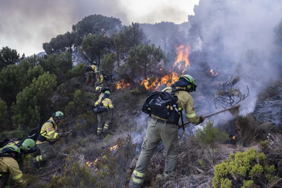 Forest firefighters work on a wildfire near the town of Jubrique, in Malaga province, Spain, Saturday, Sept. 11, 2021. Firefighting crews in southern Spain are waiting for much-needed rainfall expected on Monday that they hope can help extinguish a stubborn mega-fire that has ravaged 7,400 hectares (18,300 acres) in five days and displaced some 3,000 people from their homes. (AP Photo/Pedro Armestre)