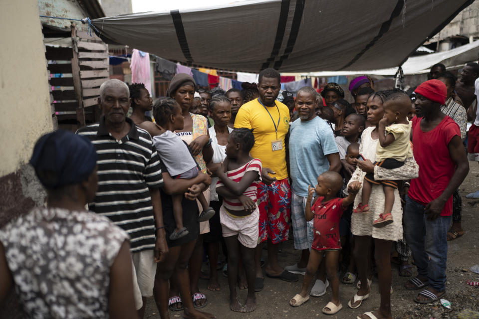 Jean-Kere Almicar poses for a picture with people who have been displaced by gang violence and are now living in his front yard, in Port-au-Prince, Haiti, Friday, June 2, 2023. Almicar, who once lived in Scranton, Pennsylvania but moved back to Haiti in 2007, uses his own money to help feed those living in his yard. (AP Photo/Ariana Cubillos)