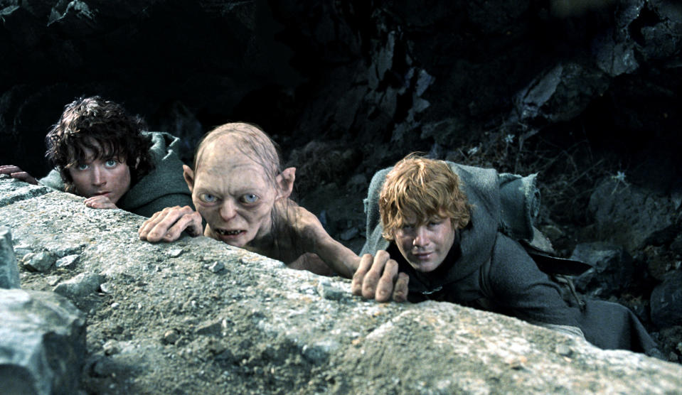 Frodo Baggins, Gollum, and Samwise Gamgee climb over a rocky ledge in a scene from "The Lord of the Rings."