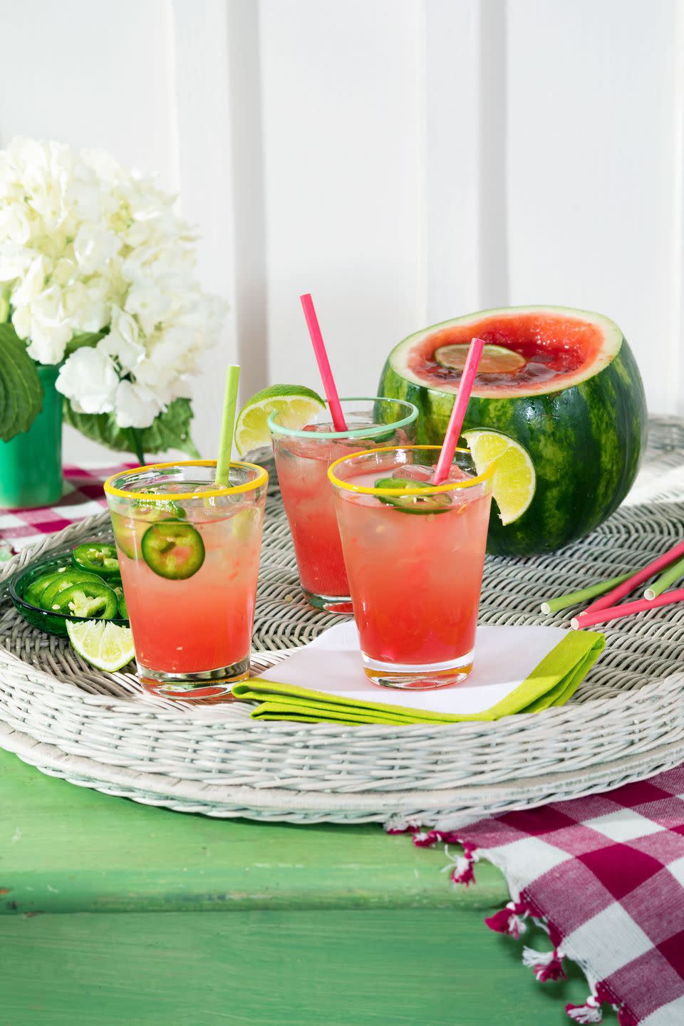 spicy watermelon cocktail in glasses garnished with sliced jalapeno and lime wedges