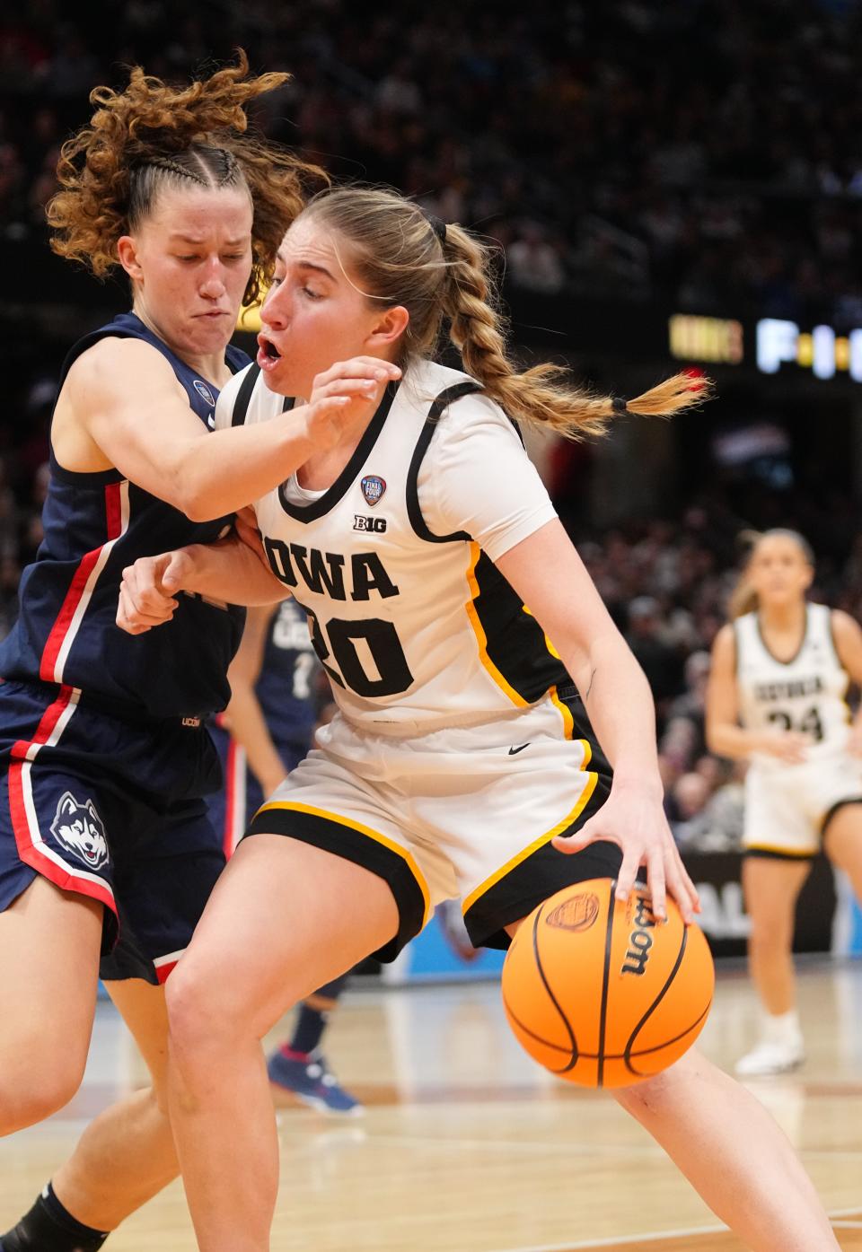 Iowa guard Kate Martin (20) drives to the basket as Connecticut's Ashlynn Shade (12) defends during Friday's national semifinal game.
