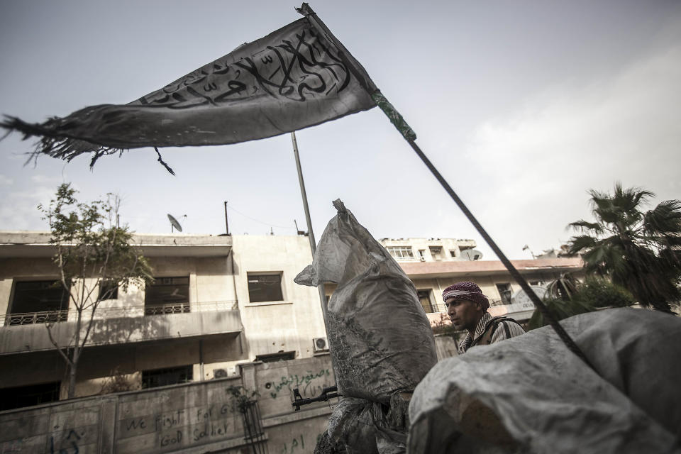 FILE - In this Saturday, Oct. 20, 2012 file photo, a rebel fighter stands guard at a checkpoint near the frontline in the Bustan al-Qasr neighborhood of Aleppo, Syria. More than two years into Syria's civil war, the once highly-centralized authoritarian state has effectively split into three distinct parts, each boasting its own flags, security agencies and judicial system. (AP Photo/Narciso Contreras, File)