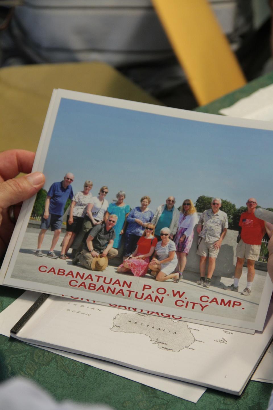A 2015 file photo shows John McConnell holding a photo from a group trip to the site of the Cabanatuan POW camp in the Philippines.