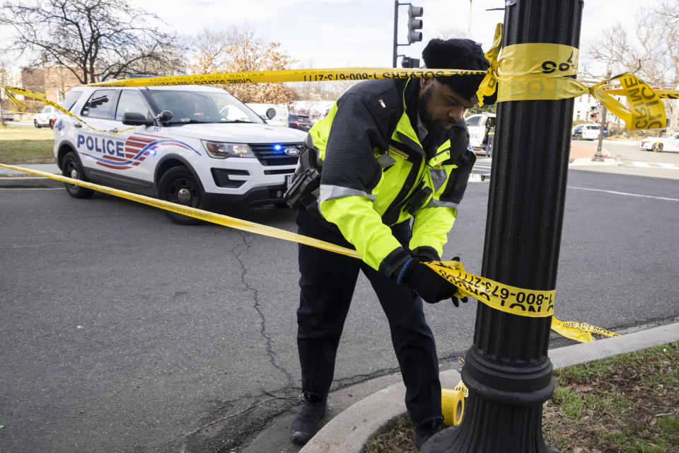 A Washington Metropolitan Police officer, puts yellow tape around the Potomac Avenue Metro Station in Southeast Washington, Wednesday, Feb. 1, 2023. An armed man shot three people, killing one, Wednesday in a morning rampage that started on a city bus and ended in a Metro tunnel after passengers attacked and disarmed him. (AP Photo/Manuel Balce Ceneta)