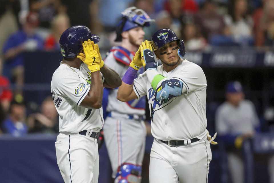 Tampa Bay Rays' Isaac Paredes, right, celebrates after his three-run home run with Randy Arozarena, left, in front of Texas Rangers catcher Jonah Heim, center, during the third inning of a baseball game Friday, June 9, 2023, in St. Petersburg, Fla. (AP Photo/Mike Carlson)