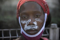 A factory worker, with paste smeared on her face to help diminish the effects of tear gas, eyes the camera during a protest demanding a salary increase, in Port-au-Prince, Haiti, Thursday, Feb. 10, 2022. The workers employed at factories that produce textiles and other goods say they make 500 gourdes ($5) a day for nine hours of work and are seeking a minimum of 1,500 gourdes ($15) a day. (AP Photo/Odelyn Joseph)