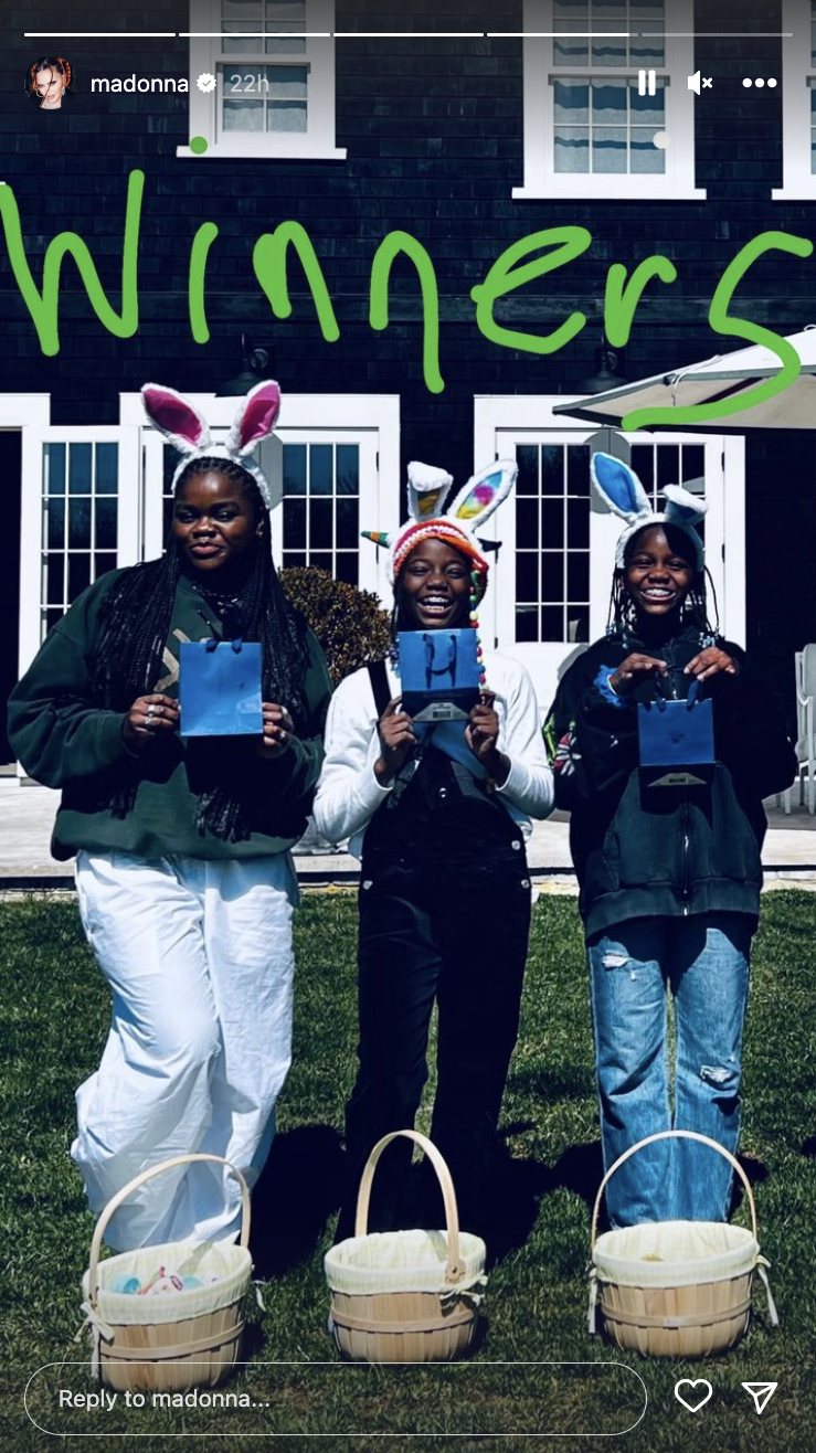 Three young Black women smile in front of a house holding blue gift bags while wearing easter bunny ears/ (@Maddona / Instagram)