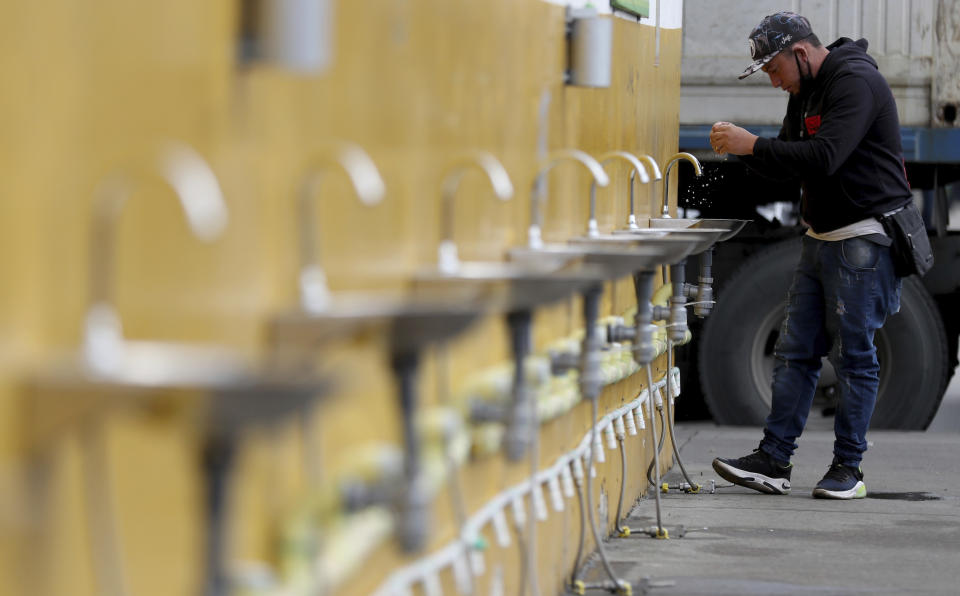 A man washes his hands amid the new coronavirus pandemic, in Corabastos, one of Latin America's largest food distribution centers, in Bogota, Colombia, Tuesday, June 23, 2020. The Corabastos market has installed 500 hand-washing stations to help curb the spread of COVID-19. (AP Photo/Fernando Vergara)