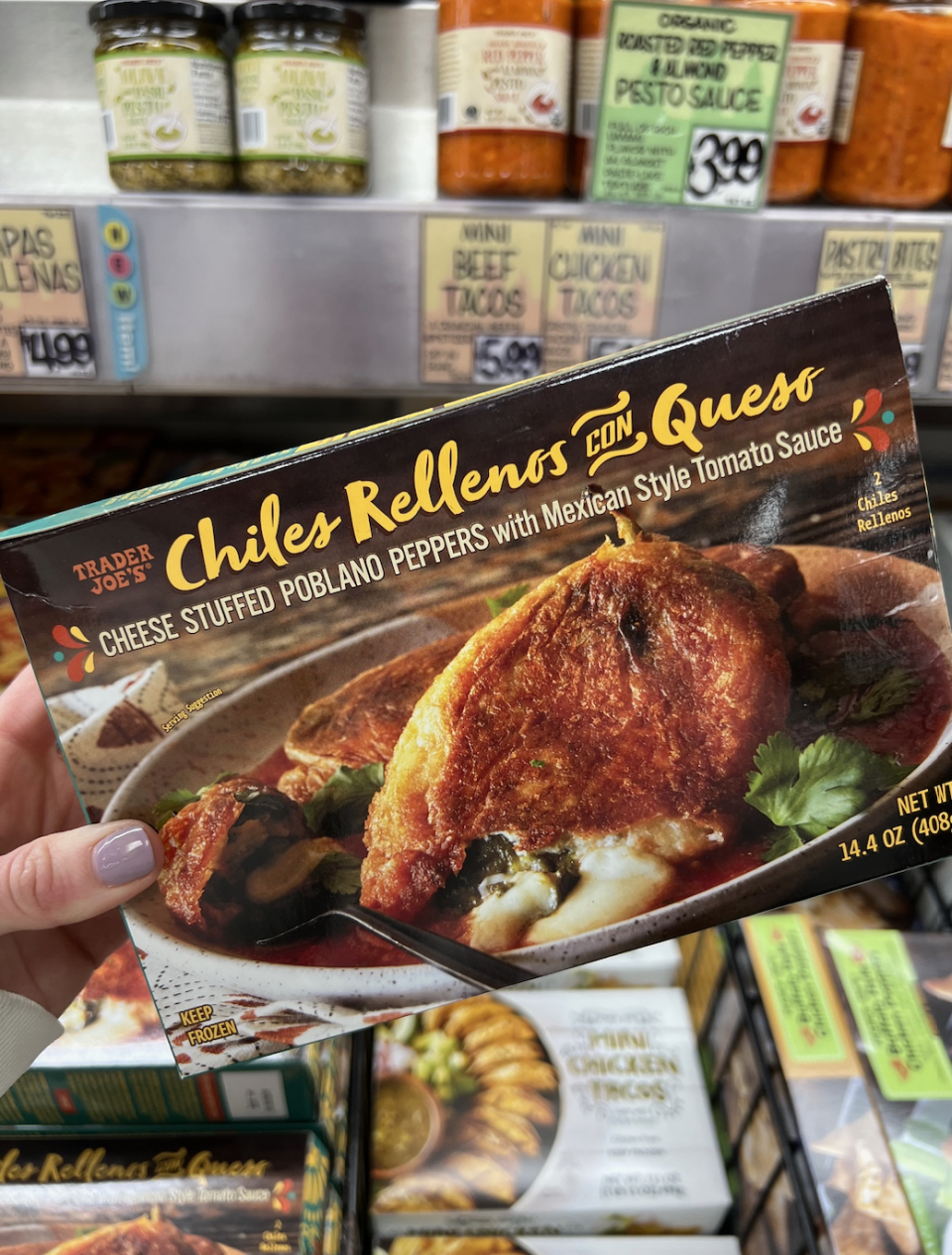 Hand holding a Trader Joe's Chiles Rellenos con Queso package in a grocery store