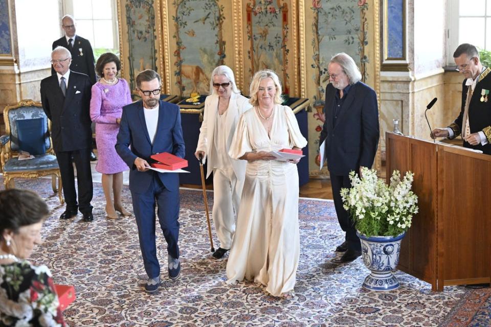 ABBA (Björn Ulvaeus, in navy suit, Anni-Frid Lyngstad, Agnetha Fältskog and Benny Andersson) beam after receiving their Royal Vasa Orders from Sweden's King Carl XVI Gustaf (far left) and Queen Silvia of Sweden (in purple dress) during a ceremony at Stockholm Royal Palace on May 31, 2024.