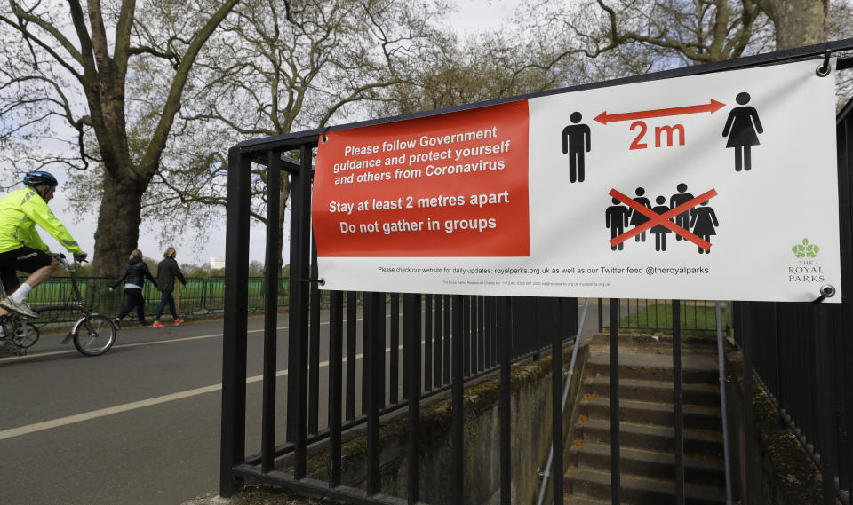 A sign in Hyde Park in London advises social distancing, as the country is in lockdown to help curb the spread of the coronavirus, Monday, April 13, 2020. The new coronavirus causes mild or moderate symptoms for most people, but for some, especially older adults and people with existing health problems, it can cause more severe illness or death. (AP Photo/Kirsty Wigglesworth)