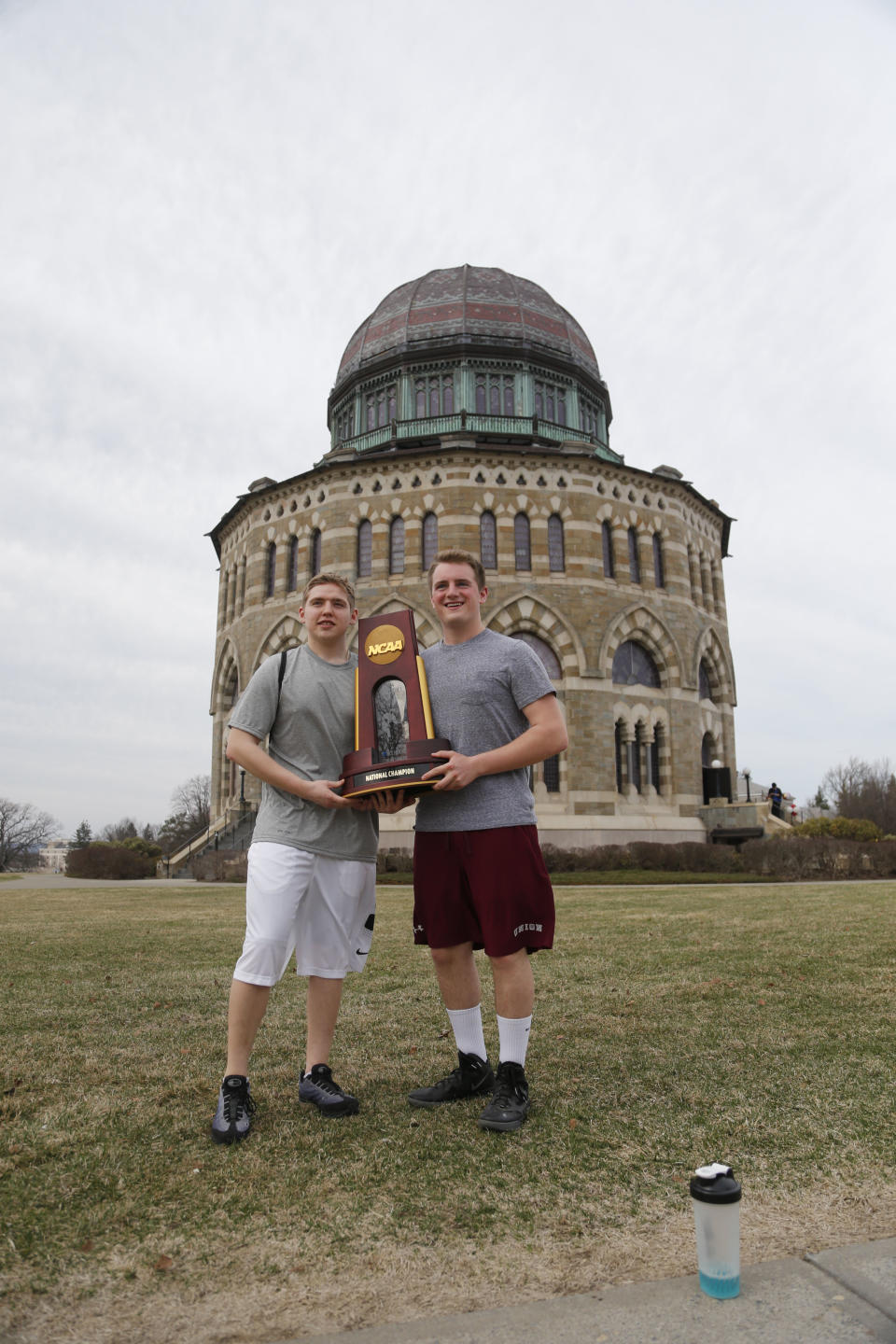 Freshmen Adam Appelbaum of Boston, left, and Liam Glennon of Schenectady, N.Y., pose with the NCAA men's hockey trophy won by Union College, in front of the Nott Memorial at Union on Monday, April 14, 2014, in Schenectady. Tiny Union, enrollment 2,200, defeated Minnesota, enrollment 48,000, Saturday for its first NCAA hockey title. (AP Photo/Mike Groll)