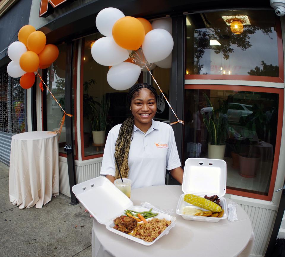 Kreyol 17 supervisor Carmina Vincent shows a couple of meals available from the restaurant on Legion Parkway in downtown Brockton on opening day was Thursday, Aug. 17, 2023. On the left is an oxtail mix and on the right is a combination of corn, plantain, ribs and mashed potatoes. The drink is a mix of tonic water, mint syrup, passion fruit juice and pineapple juice.