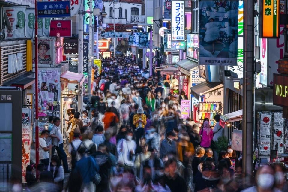 Busy street in a bustling shopping district filled with many people and various store signs and advertisements