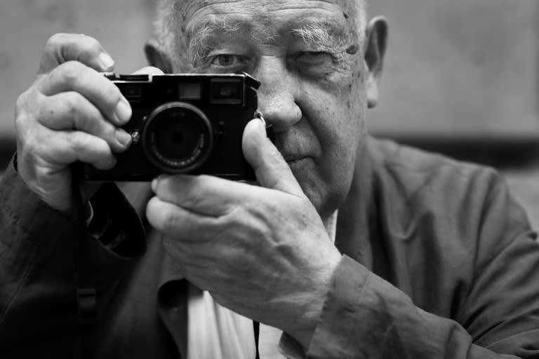 Le photographe français Raymond Depardon pose avec son appareil Leica pendant l'installation, le 24 juin 2024, à Paris, d'une exposition de certaines de ses photographies prises pendant des Jeux olympiques (JOEL SAGET)