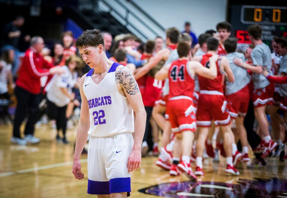 Muncie Central's Dylan Stafford walks off the court as New Palestine celebrates a one-point victory in the sectional championship game at the Muncie Fieldhouse on March 7, 2020.