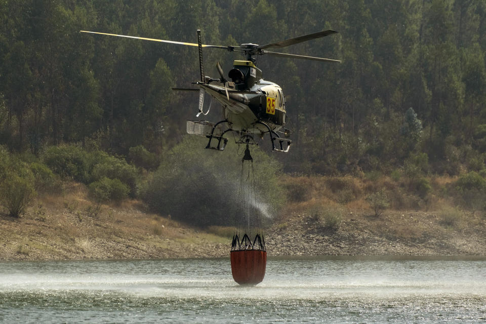 A helicopter takes water at the Vergancinho dam to extinguish a wildfire near Colos village, in central Portugal on Monday, July 22, 2019. More than 1,000 firefighters battled Monday in torrid weather against a major wildfire in Portugal, where every summer forest blazes wreak destruction. (AP Photo/Sergio Azenha)