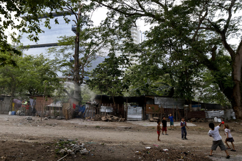 Children play in a slum adjacent to a luxury condominium towers in San Pedro Sula, Honduras, Tuesday, April 30, 2019. Municipal authorities have long wanted to clear the shacks, and during one attempt several of the' homes were torched. Human rights workers have obtained a court order protecting them for now. (AP Photo/Delmer Martinez)