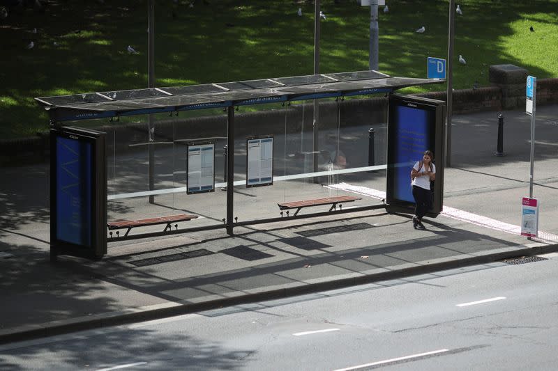 A woman stands alone on a bus stop during a workday following the implementation of stricter social-distancing and self-isolation rules to limit the spread of the coronavirus disease (COVID-19) in Sydney