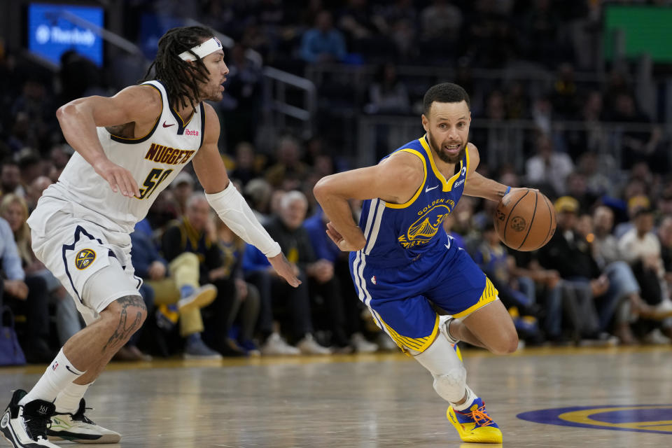 Golden State Warriors guard Stephen Curry, right, moves the ball while defended by Denver Nuggets forward Aaron Gordon during the second half of an NBA basketball game Sunday, Feb. 25, 2024, in San Francisco. (AP Photo/Godofredo A. Vásquez)