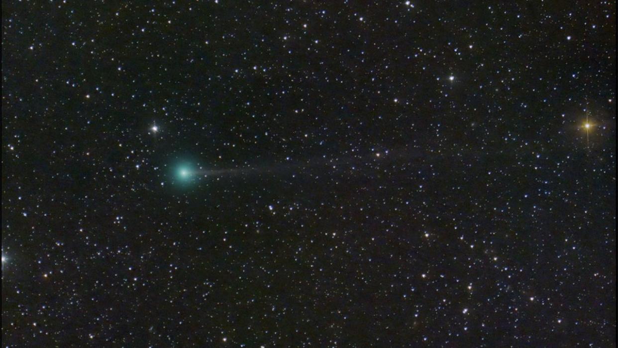  a green comet with a faint tail in the sky against a backdrop of stars 