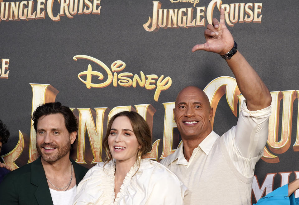 FILE - Dwayne Johnson, right, a cast member in "Jungle Cruise," flashes the Hawaiian "shaka" hand sign as he poses with fellow cast members Edgar Ramirez, left, and Emily Blunt at the world premiere of the film, July 24, 2021, at Disneyland in Anaheim, Calif. Hawaii’s “shaka” hand sign is sometimes known as the “hang loose” gesture associated with surf culture. But it was a fixture of daily life in the islands long before it caught on in California, Brazil and beyond. (AP Photo/Chris Pizzello, File)