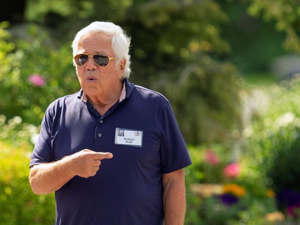 Robert Kraft points while standing outside wearing sunglasses